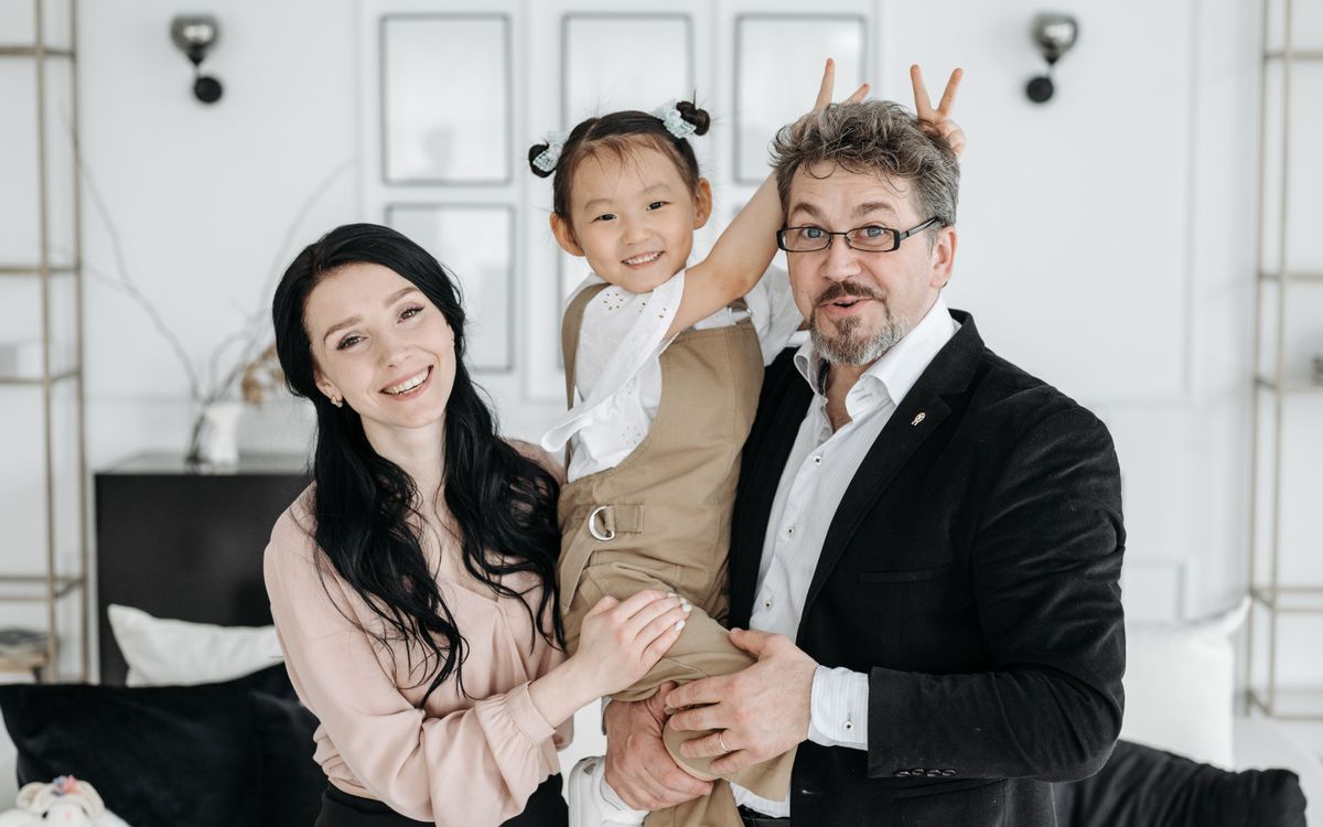 Parents and their young child smile together at home.