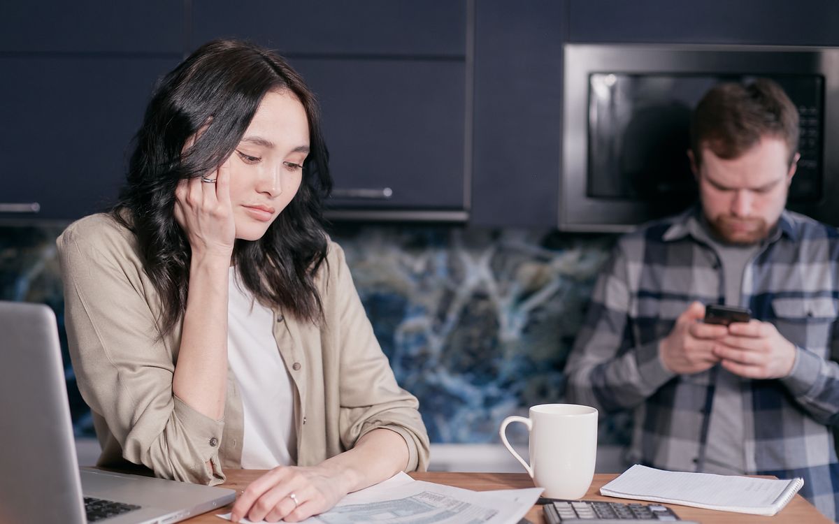 A couple looks over household bills at a kitchen table.