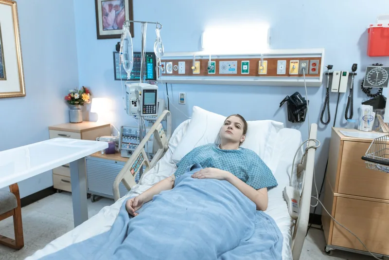 A young woman rests in a hospital bed while recovering in a quiet ward.